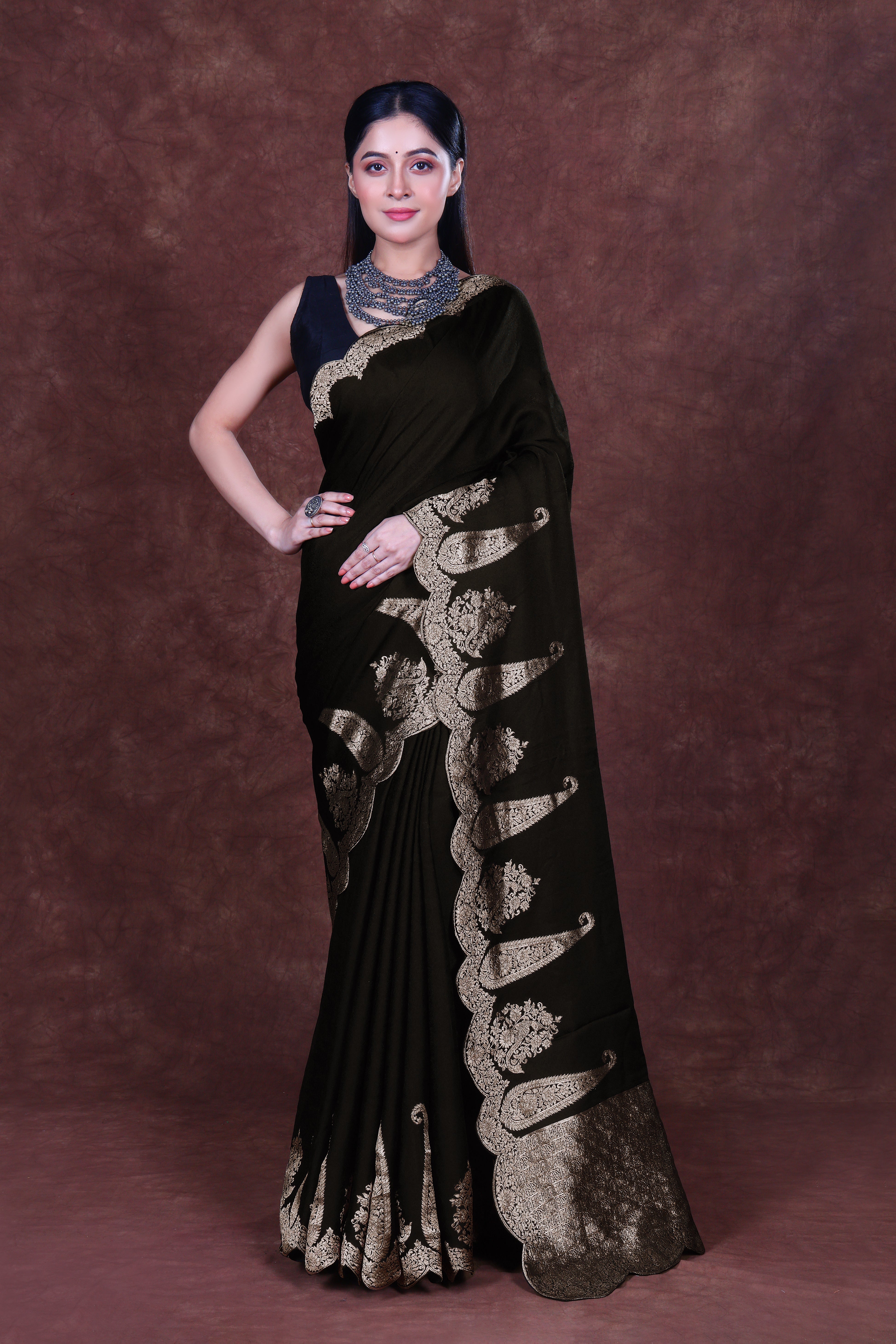 Black semi mashru saree featuring a smooth, satin-like finish with a subtle sheen, accented by delicate woven patterns and a contrasting decorative border, draping elegantly with a rich, lustrous texture.
